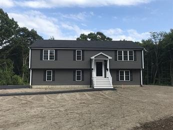 Gray two-story house with white trim, central steps, and a dirt front yard.