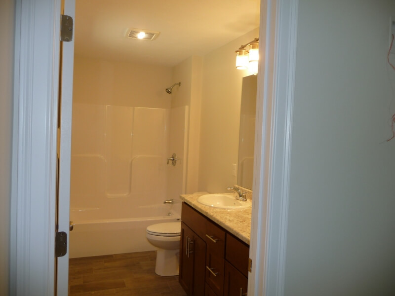 A bathroom with a bathtub, toilet, and a vanity with a sink and mirror.