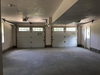 Empty two-car garage with closed white doors and a side entrance door.