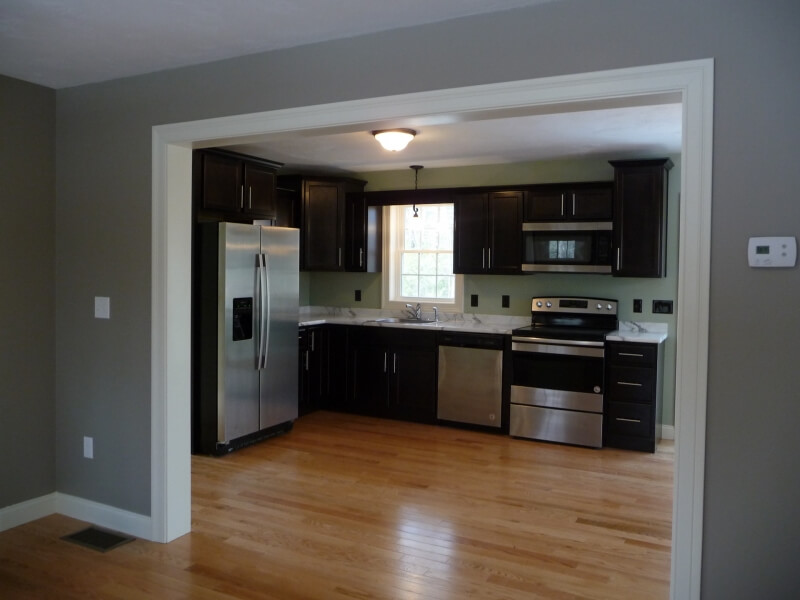 Modern kitchen with dark cabinets, stainless steel appliances, and hardwood floors.