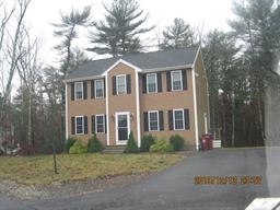 Two-story brown house with white trim, black shutters, and a driveway, surrounded by trees.