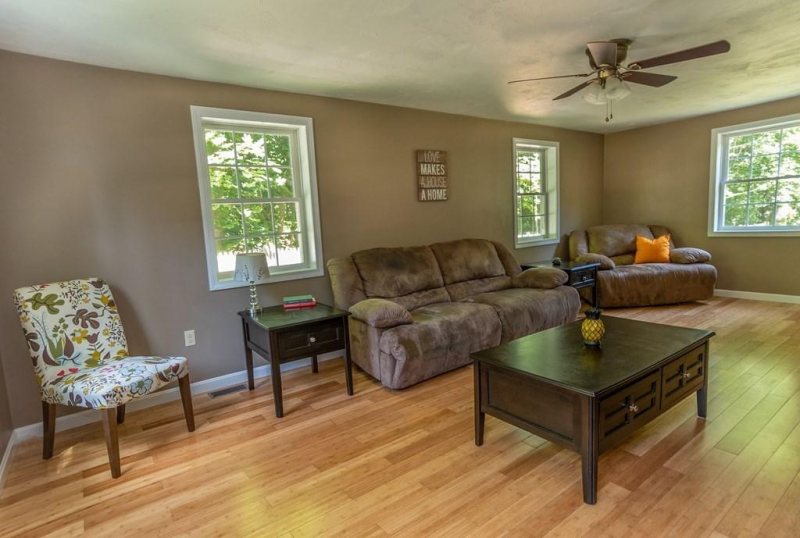Living room with brown sofas, wooden coffee table, floral chair, and large windows.