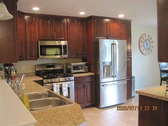 Modern kitchen with wooden cabinets, stainless steel appliances, and granite countertops.