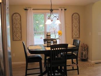 Dining area with a black table, four chairs, window, and wall decor on both sides.