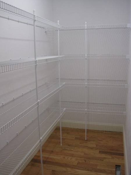 Empty pantry with white wire shelving on both walls and a hardwood floor.