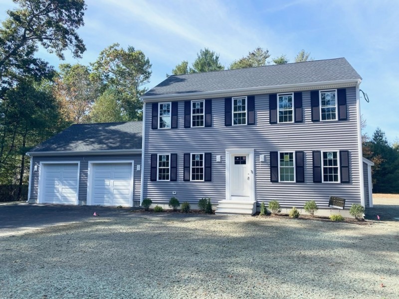 Two-story gray house with black shutters, double garage, and a gravel driveway.