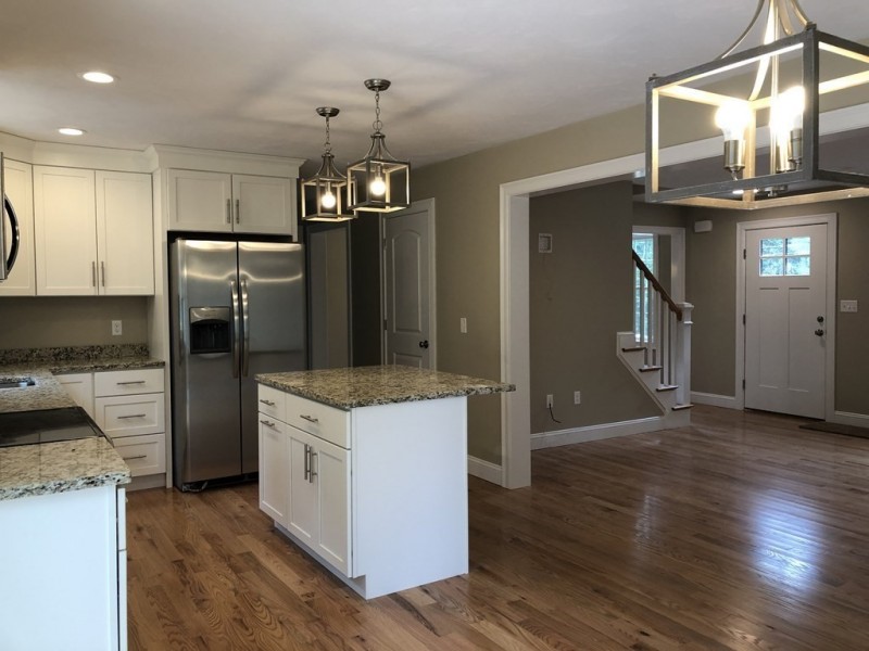 Modern kitchen with white cabinets, island, stainless steel appliances, and hardwood floors.