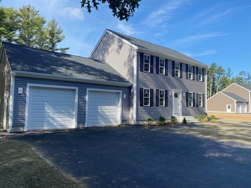 Two-story gray house with double garage, black shutters, and a paved driveway.