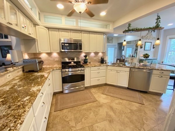 Modern kitchen with granite countertops, stainless steel appliances, and beige tile flooring.