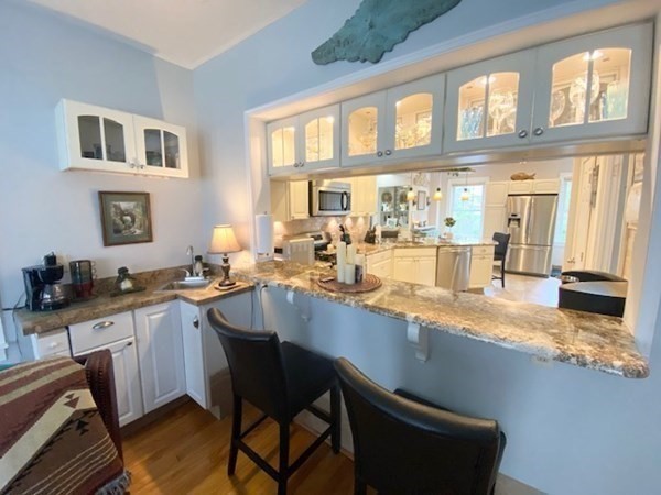 Bright kitchen with bar seating, granite countertop, and glass-front cabinets.