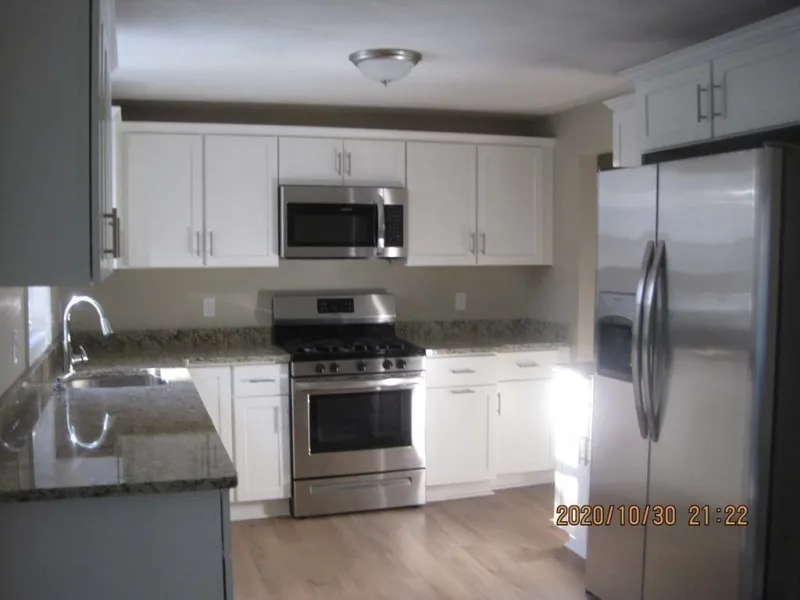 Modern kitchen with white cabinets, stainless steel appliances, and granite countertops.