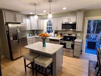 Modern kitchen with stainless steel appliances, island, and fresh flowers in a vase.