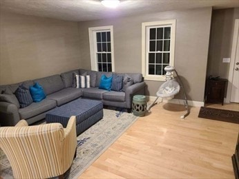 Living room with gray sectional sofa, blue ottoman, striped chair, and baby swing.