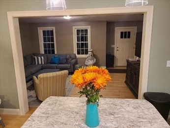 Orange flowers in a turquoise vase on a kitchen island, with a living room in the background.