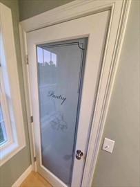 White pantry door with frosted glass panel and decorative text reading Pantry.