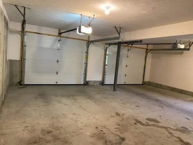 Empty two-car garage with concrete floor, two garage doors, and overhead lighting.