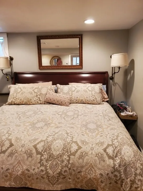 A neatly made bed with patterned bedding, pillows, and a mirror above the headboard.