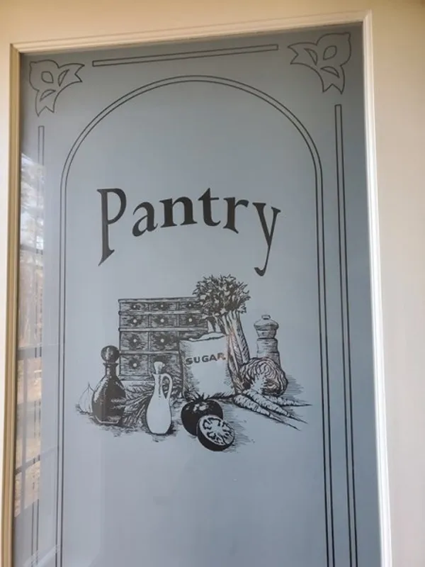Glass pantry door with vintage-style illustrations of kitchen items and the word Pantry.