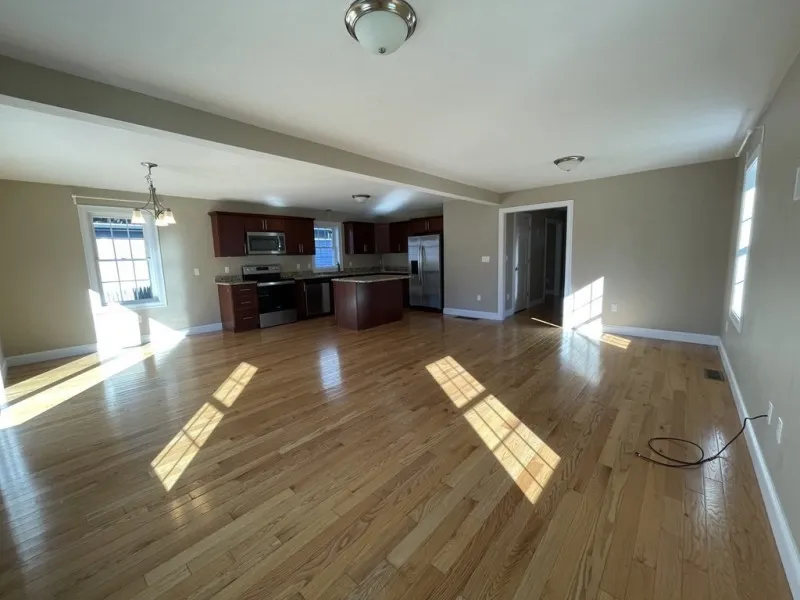 Spacious open-plan kitchen and living area with hardwood floors and stainless steel appliances.