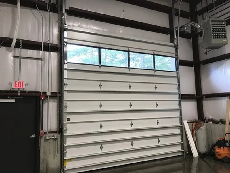 Industrial garage door with windows at the top, closed inside a warehouse building.