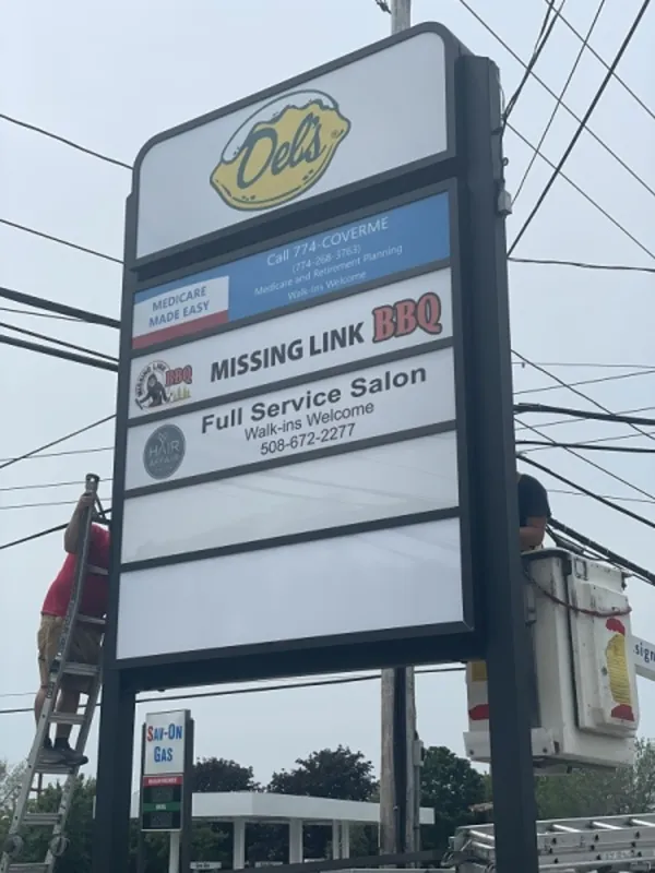 A tall roadside sign displays ads for a BBQ place, salon, and healthcare service.