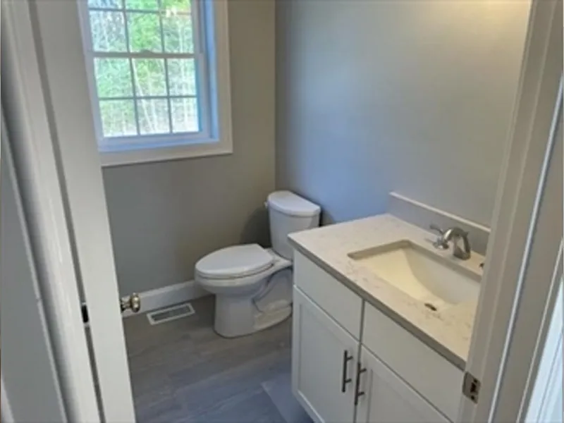 Small bathroom with a white toilet, sink vanity, and window letting in natural light.