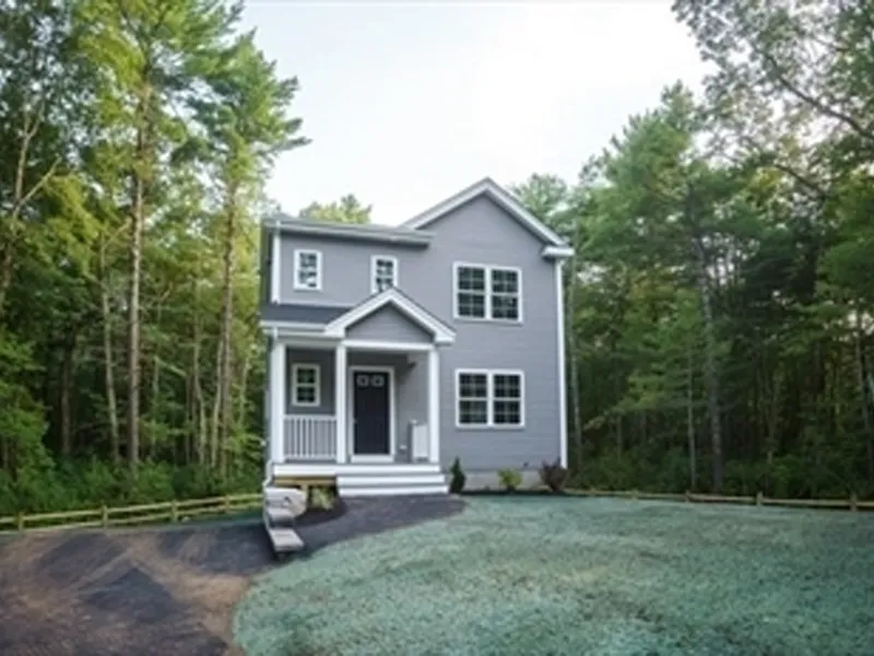 Gray two-story house with a front porch, surrounded by trees and a grassy yard.