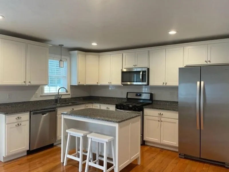 Modern kitchen with white cabinets, stainless steel appliances, and a small island.