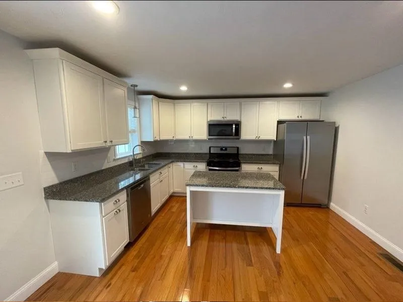 Modern kitchen with white cabinets, granite countertops, and stainless steel appliances.