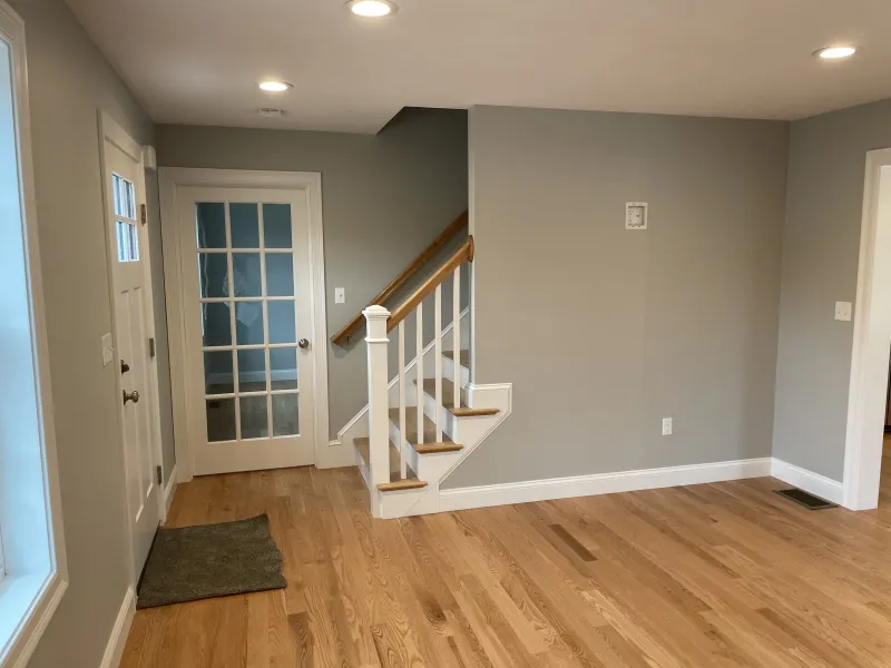 Living room with hardwood floors, a staircase, and a door with glass panels.