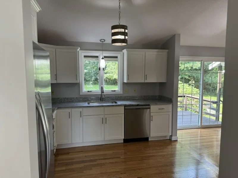 Bright kitchen with white cabinets, stainless appliances, and window view of a green yard.