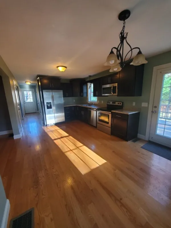 Modern kitchen with dark cabinets, stainless steel appliances, and hardwood floors.