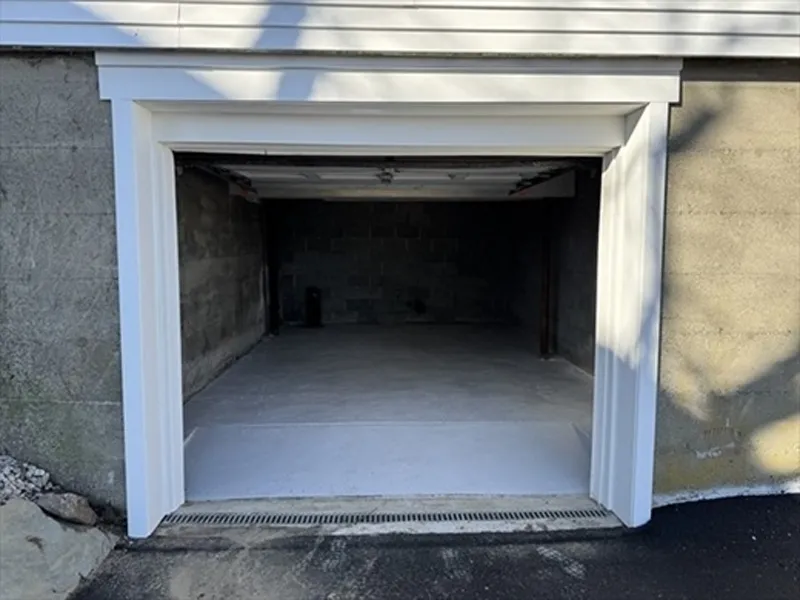 Open garage door revealing an empty, clean concrete-floored garage interior.