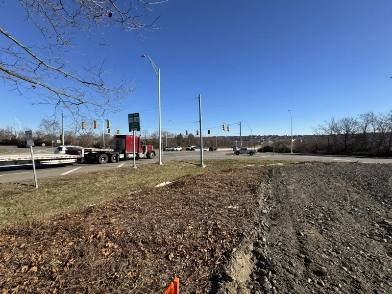 A red semi-truck turns at a busy intersection under a clear blue sky.