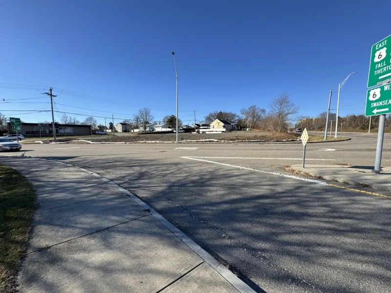 Sunny day at a quiet intersection with road signs, sidewalks, and clear blue sky.