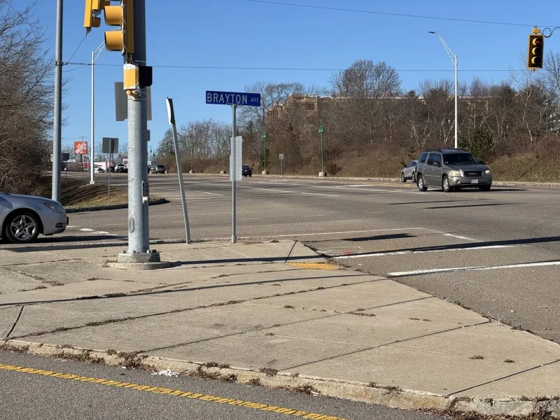 Intersection with cars, traffic lights, and a street sign reading BRAYTON AVE on a sunny day.