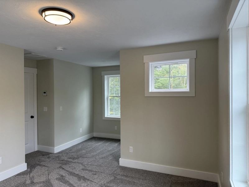 Empty room with two windows, light gray walls, and carpeted floor with geometric pattern.