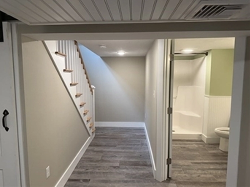 Basement hallway with stairs and a bathroom with toilet and shower on the right.