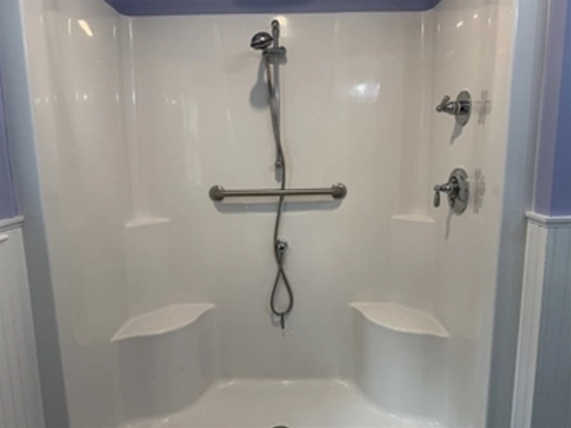 White walk-in shower with built-in seats, grab bar, handheld showerhead, and controls.