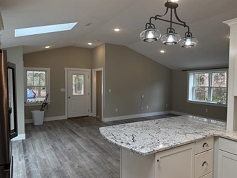 Open concept living area with gray floors, white walls, and a granite kitchen island.