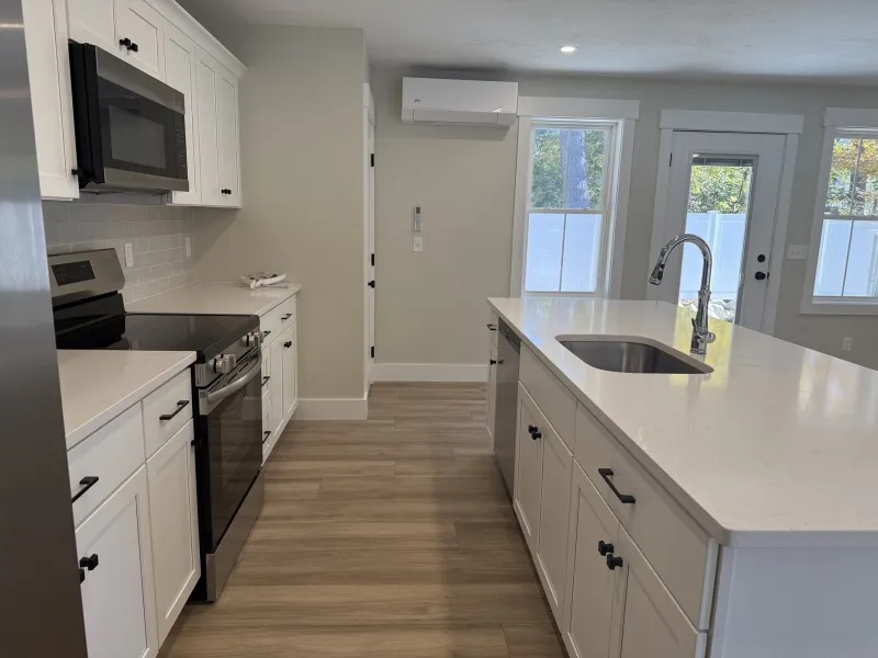 Modern kitchen with white cabinets, island sink, and stainless steel appliances.