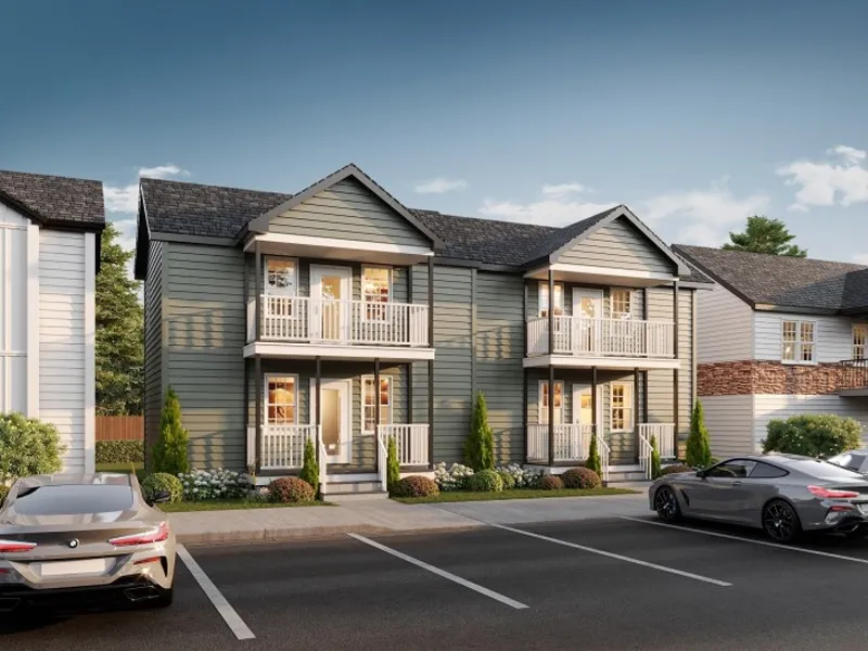 Two-story gray townhouse with balconies, parked cars in front, and landscaped shrubs.